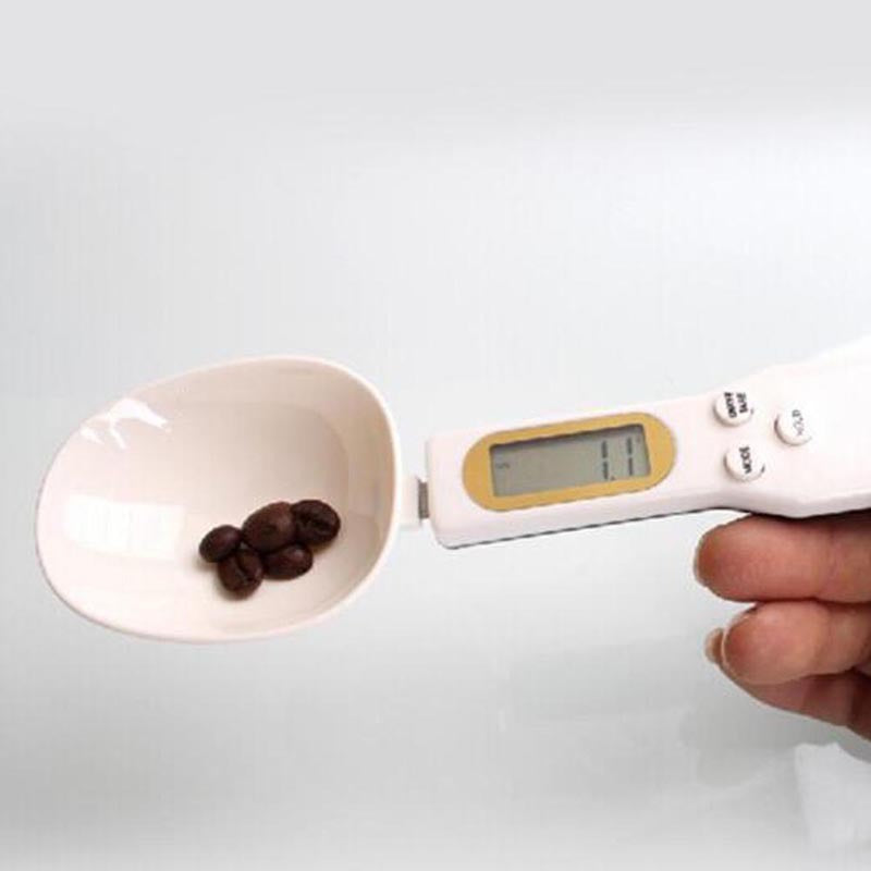 Digital kitchen scale with a bowl containing coffee beans on a white background